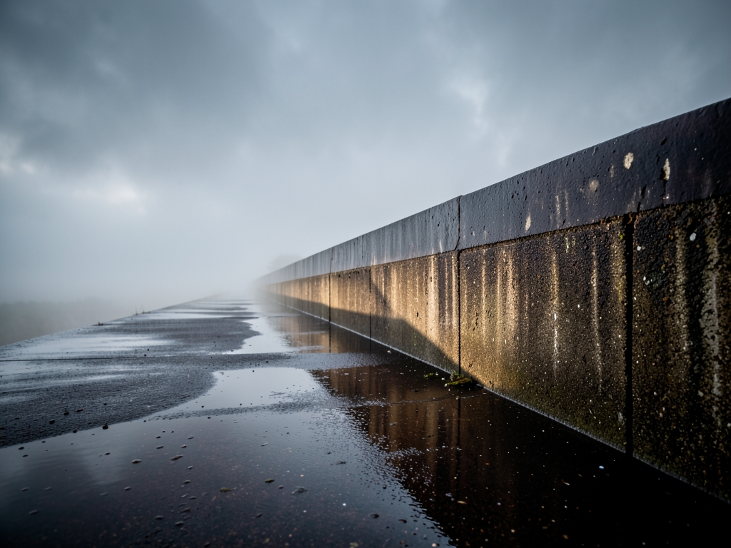 rain soaked concrete perimeter wall stretching into under overcast