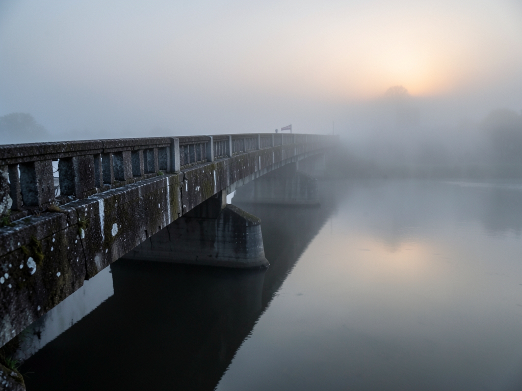long concrete bridge stretching into low hanging over still