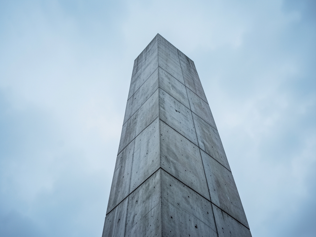 lone concrete tower rising through overcast skies facade