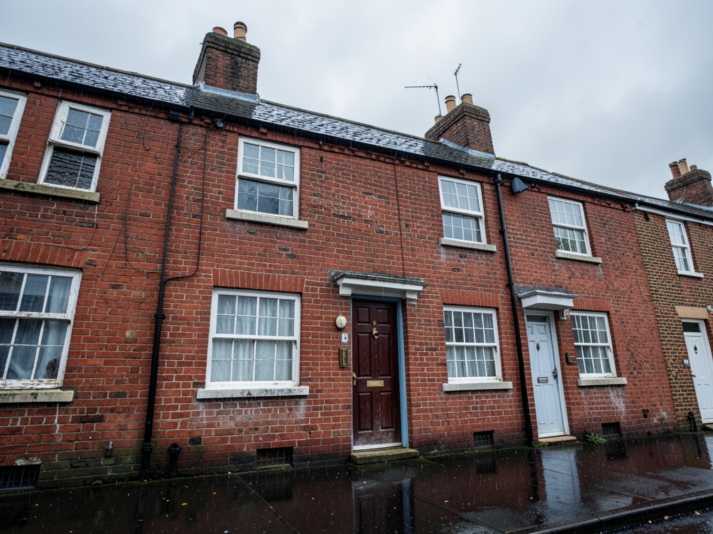 modest British red brick terraced house beneath overcast skies