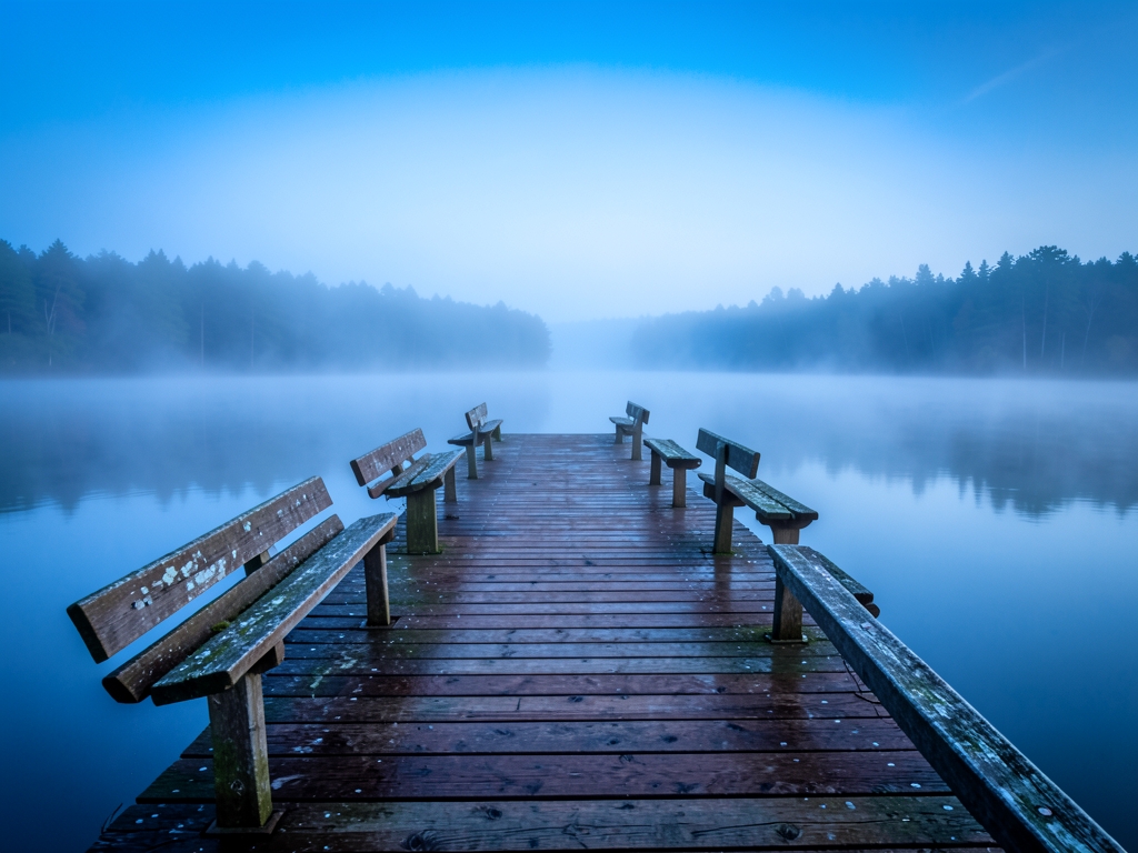 Quiet misty lakeside dock dawn with still water