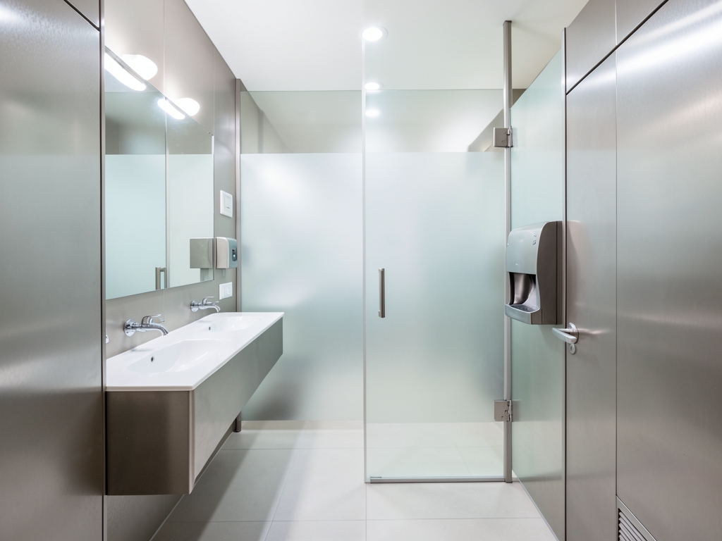 Contemporary commercial restroom interior with brushed metal fixtures