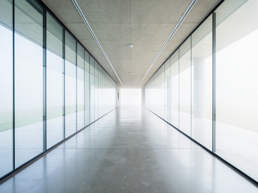 long glass and concrete corridor stretching into soft diffused daylight