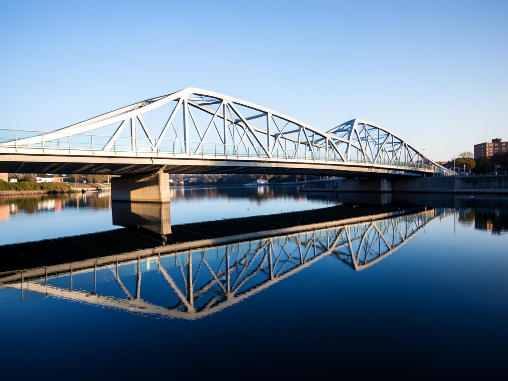 sleek silver and glass bridge arcs across placid mirror like channel