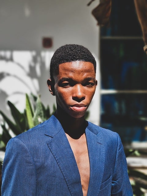 close up portrait black male model fierce stare intense expression blue suit fashion close up dominant look editorial headshot bold